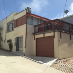 A house with a garage and balcony in the middle of it.