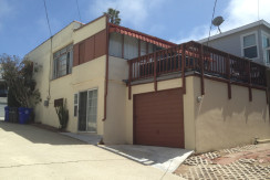 A house with a garage and balcony in the middle of it.