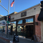 A street view of a restaurant with an american flag on the corner.