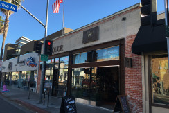 A street view of a restaurant with an american flag on the corner.