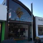 A store front with palm trees on the side of it.