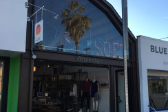 A store front with palm trees on the side of it.