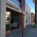 A street view of a store front with a red pole.