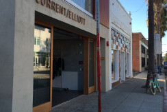 A street view of a store front with a red pole.