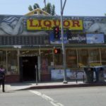 A liquor store with a person walking on the sidewalk.