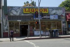 A liquor store with a person walking on the sidewalk.