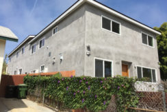 A gray building with green plants growing on it.