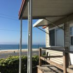 A porch with a view of the ocean and beach.