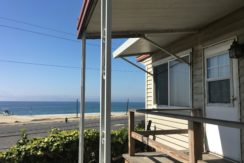 A porch with a view of the ocean and beach.